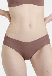 Bruna sömlösa hipsterunderkläder med en slät textur, låg midja och elastisk linning, utan synliga sömmar eller mönster.