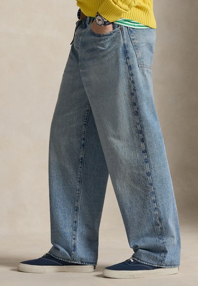 Svetlo modre kavbojke z ohlapnimi hlačnicami iz jeansa, z bledim efektom, dvema prednjima žepoma in obute v temno modre superge.