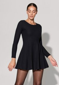 Abito lungo a maniche lunghe ribattuto nero con gonna svasata, dotato di scollatura rotonda e corpino aderente, texture liscia e orlo che arriva al ginocchio.