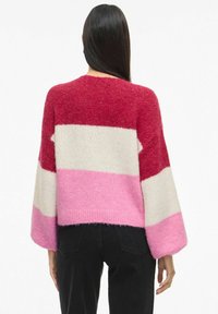 Maglione lavorato a maglia con un design ampio caratterizzato da righe orizzontali rosse, bianche e rosa. La trama morbida e le maniche larghe completano la lunghezza cropped.