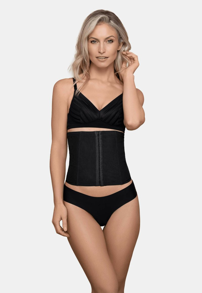 Soutien-gorge taille noire avec une fermeture éclair à l'avant, présentant une texture lisse et un design structuré, porté par-dessus un soutien-gorge noir et un bas de bikini.