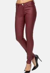 Bordeaux skinny jeans van gladde, elastische stof, met een mid-rise taille en een klassieke vijf-pocket ontwerp, gecombineerd met zwarte hakken.