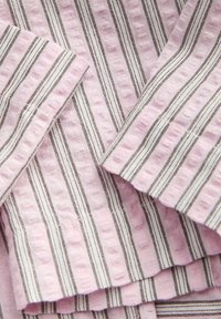 Blødt tekstureret stof med lodrette striber i lyserød, hvid og brun i en stablet rækkefølge.