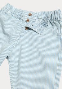 Hellblaue und weiße gestreifte Baumwollhosen mit einem elastischen Bund, die drei braune Knöpfe und Seitentaschen haben.