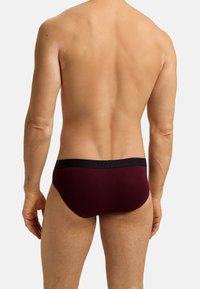 Burgunderfarbene Unterhosen mit einem schwarzen elastischen Bund. Der Stoff wirkt glatt und eng anliegend, entworfen für Komfort und Unterstützung.