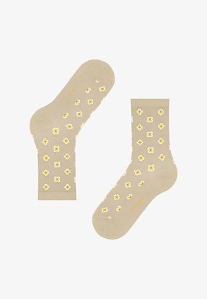 Calze beige con motivo ripetuto di piccoli fiori bianchi e gialli a quattro petali, con sottile scritta arancione del marchio su suola e punta.