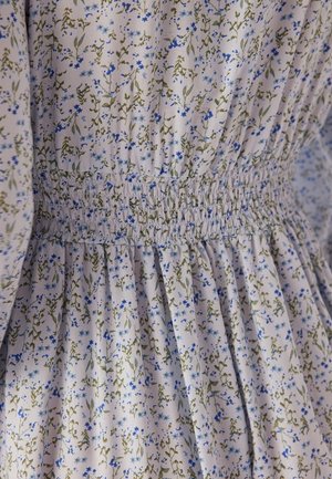 Bloemige jurk van lichte stof met een klein blauw en groen bloemenpatroon, gerimpelde tailleband en geplooide details bij de zoom.