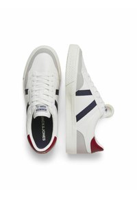 Witte sneakers met marineblauwe en rode accenten, voorzien van een vetersluiting, gladleer en een gestructureerde rubberen zool voor grip.