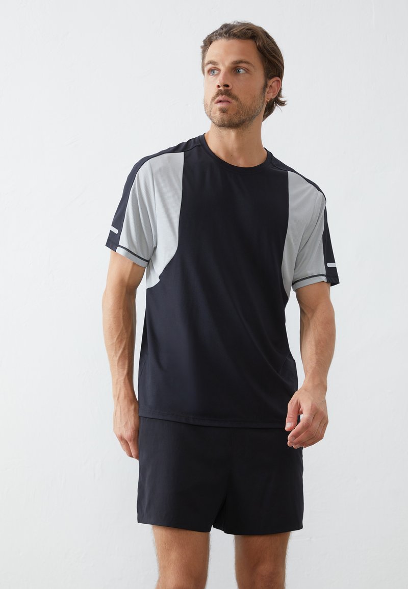 Schwarz sportliches T-Shirt mit hellgrauen Akzenten, kurzen Ärmeln und einem lockeren Schnitt. Glattes Material mit leichter Textur, kombiniert mit passenden Shorts.