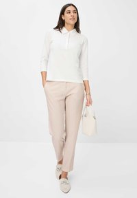 Weißes Langarm-Polohemd, rosa karierten Hosen, hellbeige Handtasche und beige Loafers mit Kettendetails. Schlichte, moderne Designelemente.