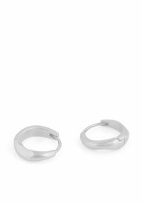 Silverfärgade kreolörhängen med en slät, polerad yta. Rund form med en lätt vridning vid öppningen. Lätt metalldesign.