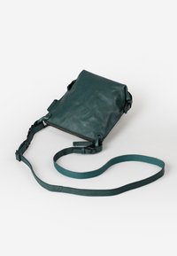 Borsa a tracolla in pelle verde acqua con pattina pieghevole, chiusura con zip, tracolla regolabile e dettagli metallici. Texture liscia, design minimalista.