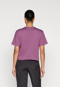 Κοντομάνικο, cropped t-shirt από βαμβάκι σε μωβ χρώμα. Απλός στρογγυλός λαιμός και άνετη εφαρμογή. Φορεμένο με φαρδιά μαύρη παντελόνια. Απλό χωρίς ορατά σχέδια.