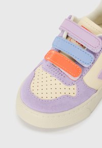 Sko med en blanding av lilafarget semsket skinn og kremfarget lær, med blå, oransje og rosa borrelåser og perforert design for pusteevne.