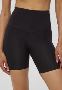 Shorts da bici neri a vita alta realizzati in tessuto liscio e elasticizzato; gamba di lunghezza media senza cuciture o decorazioni visibili.