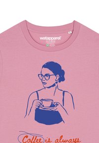 Roze T-shirt met een blauwe afbeelding van een vrouw die een kopje en schotel vasthoudt, met de tekst "Koffie is altijd" in het rood.