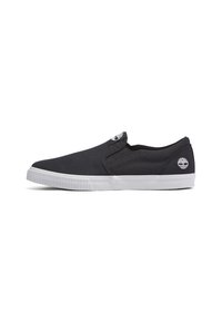 Baskets slip-on noires en toile avec semelle en caoutchouc blanche. Présentent un logo sur la languette et le talon, un tissu lisse, et un design élégant et minimaliste.