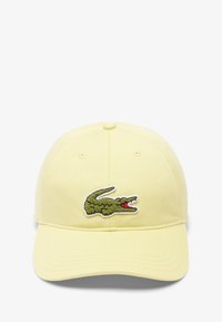 Gorra de algodón amarilla con forma redondeada, que presenta un logo bordado de cocodrilo verde con acentos rojos en la parte frontal.