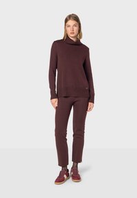 Bordeaux coltrui met ribbelzoom, gecombineerd met bijpassende strakke broek en bordeaux sneakers met lichte zolen.