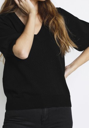 Schwarzer Pullover mit V-Ausschnitt, kurzen Ärmeln und strukturiertem Muster. Rippbündchen an Saum und Ärmeln, aus einem gestrickten Stoff gefertigt.