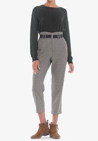 Svart långärmad topp, högmidjade rutiga byxor med bälte. Bruna ankelstövlar med dragkedja. Slätt tyg, skräddarsydd passform.