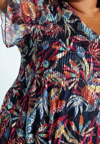 Robe en tissu transparent multicolore avec un motif floral, des manches courtes à volants et des détails froncés le long de l'encolure et du corsage.
