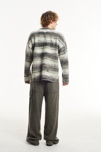 Pūrų, per didelis megztinis su tekstūra, žaliomis ir pilkomis juostelėmis, derinamas su laisvai krentančiomis tamsiai pilkomis kelnių. Paprastas dizainas ir atsipalaidavęs siluetas.