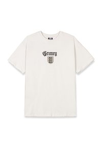 Camiseta de algodón blanca con el texto gótico negro "Grimey" en la parte superior y un pequeño diseño de escudo con elementos estilizados y un intrincado detalle.