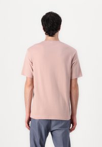 Helles rosa Baumwoll-T-Shirt mit Rundhalsausschnitt und kurzen Ärmeln, das eine lockere Passform und glatte Textur bietet. Rückansicht dargestellt.