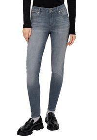 Vaqueros ajustados en denim gris claro con un lavado desgastado, que cuentan con bolsillos delanteros y un cierre clásico de botón. Combinados con zapatos negros brillantes.