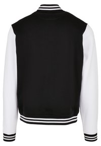 Veste universitaire noire et blanche avec un col côtelé, des poignets rayés et une coupe décontractée. Le dos est en tissu noir uni avec des manches contrastantes.