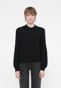 Black knit sweater with a round neck, long balloon sleeves, fitted cuffs, and a ribbed waistband. Minimalist design with no visible patterns.