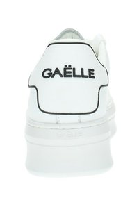 Sneaker bianca con suola spessa, finitura testurizzata e marchio nero "GAËLLE" sul retro. Presenta una tomaia liscia e dettagli in contrasto.