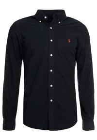 Černá košile s dlouhým rukávem a klasickým límečkem. Má bílé knoflíky a malé červené logo na levé hrudi. Hladká textura látky.