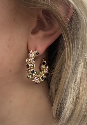 Boucles d'oreilles en or en forme de créoles ornées de pierres précieuses multicolores, y compris du rose, du vert et du violet, avec un design floral orné et des accents texturés.