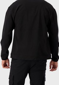 Czarna kurtka z długimi rękawami, elastycznymi mankietami i prostym, bezszwowym tyłem. Wykonana z gładkiej, nieteksturowanej tkaniny.