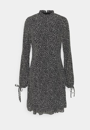 Schwarzes Kleid mit einem weißen abstrakten Muster, hohem Kragen, langen Puffärmeln mit Bindungen an den Handgelenken und einer lockeren Passform.