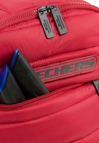 Mochila roja acolchada con doble tirador negro en el zipper. Amortiguación negra visible en el interior, junto con acentos azules en los componentes de plástico.