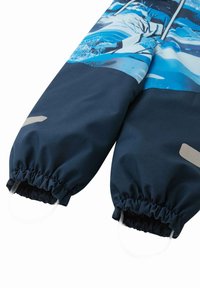 Manga de abrigo azul marino con puños elásticos y cordones. Presenta un diseño gráfico colorido de patrones en azul y blanco en la parte superior.