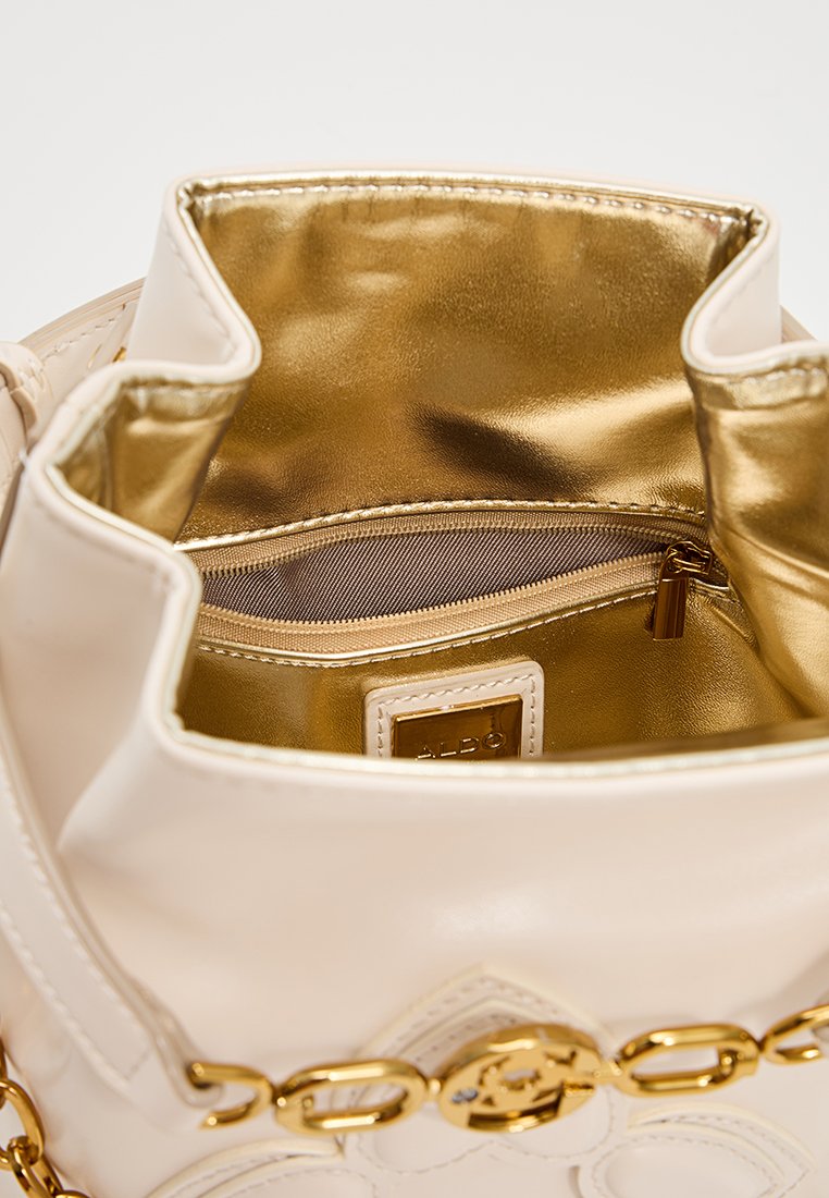 Cremfarbene Kunstleder-Handtasche mit metallisch goldfarbener Fütterung; verfügt über eine Reißverschlusstasche und eine dekorative goldene Kettenakzent.