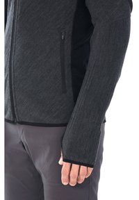 Giacca nera e strutturata con zip completa, dotata di foro per il pollice nel polsino, vestibilità aderente e con rifiniture nere a contrasto lungo le cuciture.