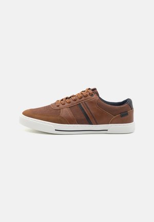 Zapatilla deportiva marrón de cuero con cordones, suela blanca, detalle de raya negra en el lateral y acento negro en el talón.