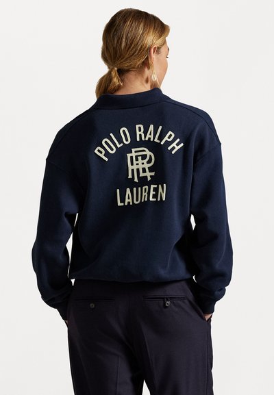 Pulover navy cu guler, având text crem brodat "POLO RALPH LAUREN" și un logo pe spate. Material moale cu o croială relaxată.