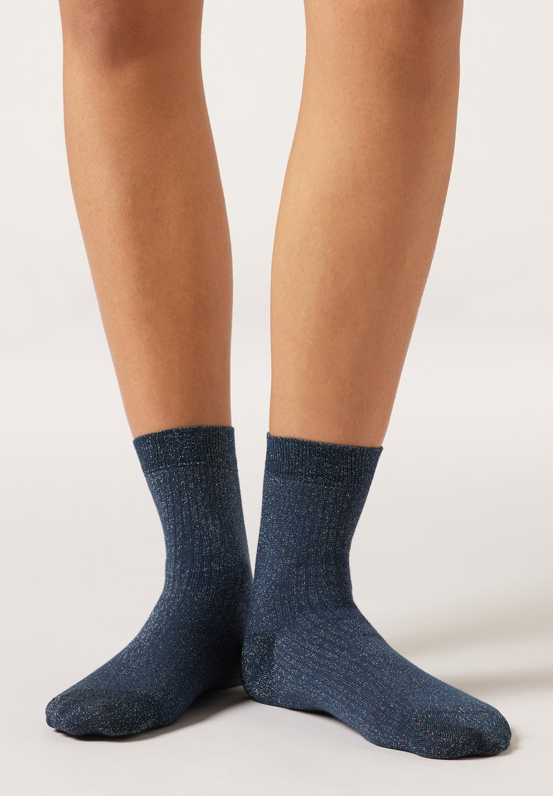 Calzini blu navy con una texture a coste e pagliuzze metalliche, caratterizzati da un polsino testurizzato alla caviglia e una soletta liscia.