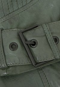 Grüner Ledergürtel mit strukturiertem Finish, ausgestattet mit einer dunkelmetallenen Schnalle und Ösen-Details. Die genähten Nähte sind sichtbar.