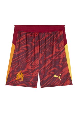 Røde og gule mønstrede fodboldshorts med elastisk talje, der har et logo og et Puma-emblem i gult nederst til højre.