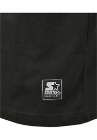 Fekete pamut póló, az alsó elülső részen egy négyzet alakú textilcímkével, rajta a "STARTER" és "BLACK LABEL" felirat fehér színben.