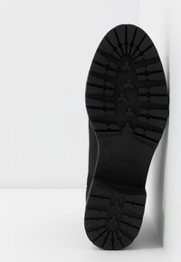 Semelle de bottine noire avec motif de crampons profond et robuste, taille 37, sur fond blanc.
