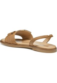 Sandalias de cuero color tostado con suela plana, que cuentan con dos correas anchas y una correa estrecha en el talón. Detalles en tono dorado en la parte superior.
