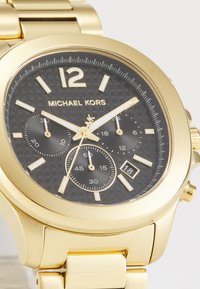 Goldfarbene Edelstahl-Uhr mit schwarzem strukturiertem Zifferblatt, drei Unterzifferblättern, goldenen Stundenmarkierungen und einem Datumsdisplay bei 6 Uhr.